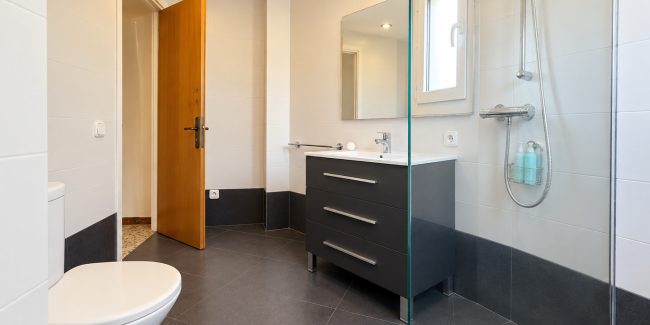 Baño moderno con ducha de cristal y vanidad gris