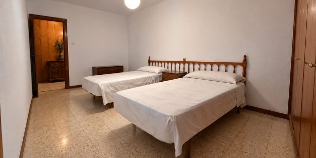 Dormitorio clásico con dos camas y armario de madera