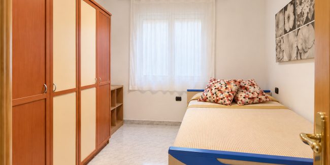 Dormitorio luminoso con cama y armario de madera