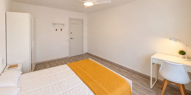 Dormitorio minimalista con manta dorada