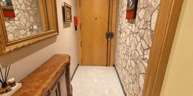 Recibidor clásico con espejo dorado y puerta de roble